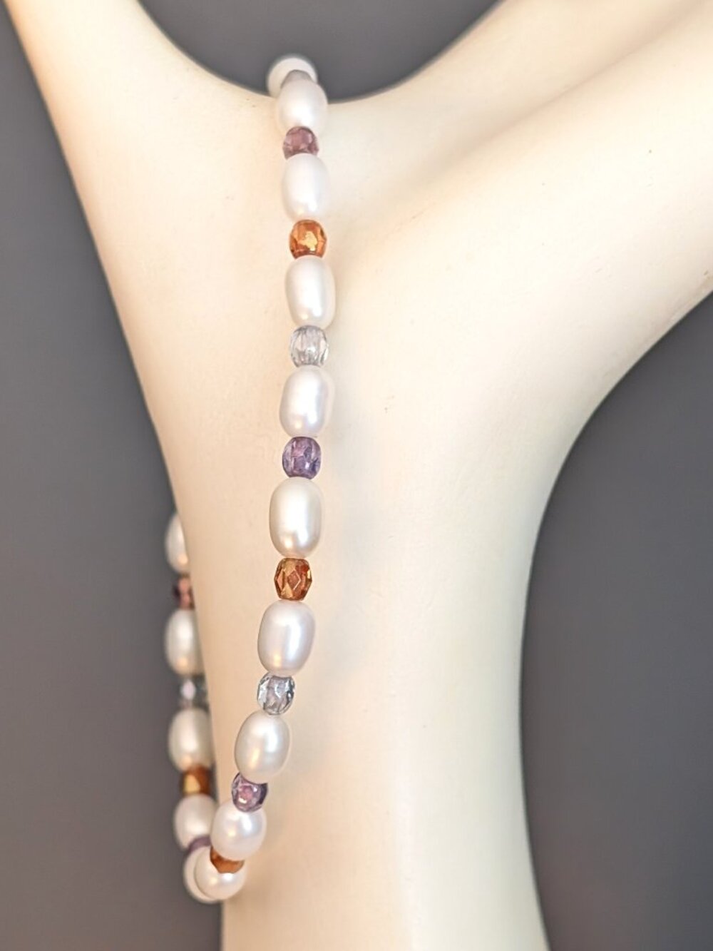 Delicate faux pearl bracelet with orange, purple, and blue-gray crystal accents